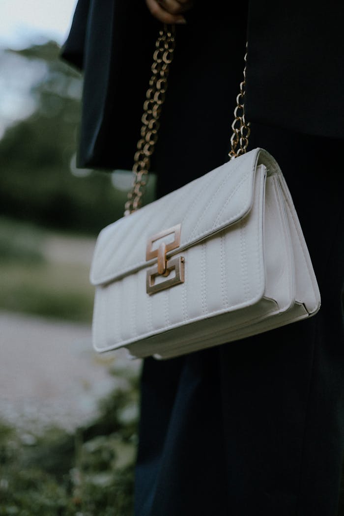 gallery-2 Stylish white handbag with gold chain details, perfect for any occasion.